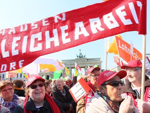 Teilnehmer der Kundgebung des Deutschen Gewerkschaftsbundes DGB stehen am 20.03.2015 am Brandenburger Tor in Berlin anlässlich des "Equal Pay Day" mit Transparenten zusammen.