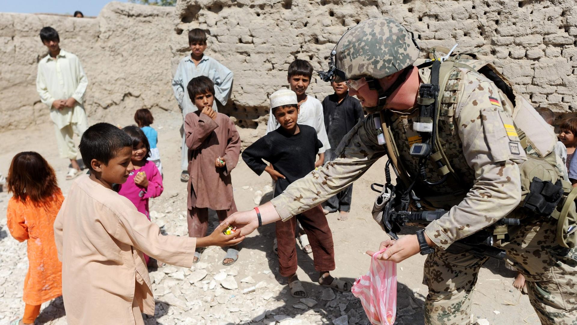 Bundeswehrsoldaten verteilen im Distrikt von Charah Darreh nahe Kundus während einer Patroillle Bonbons an Kinder. Die Soldaten suchten nach versteckten Sprengfallen und deren Urhebern. (August 2011)