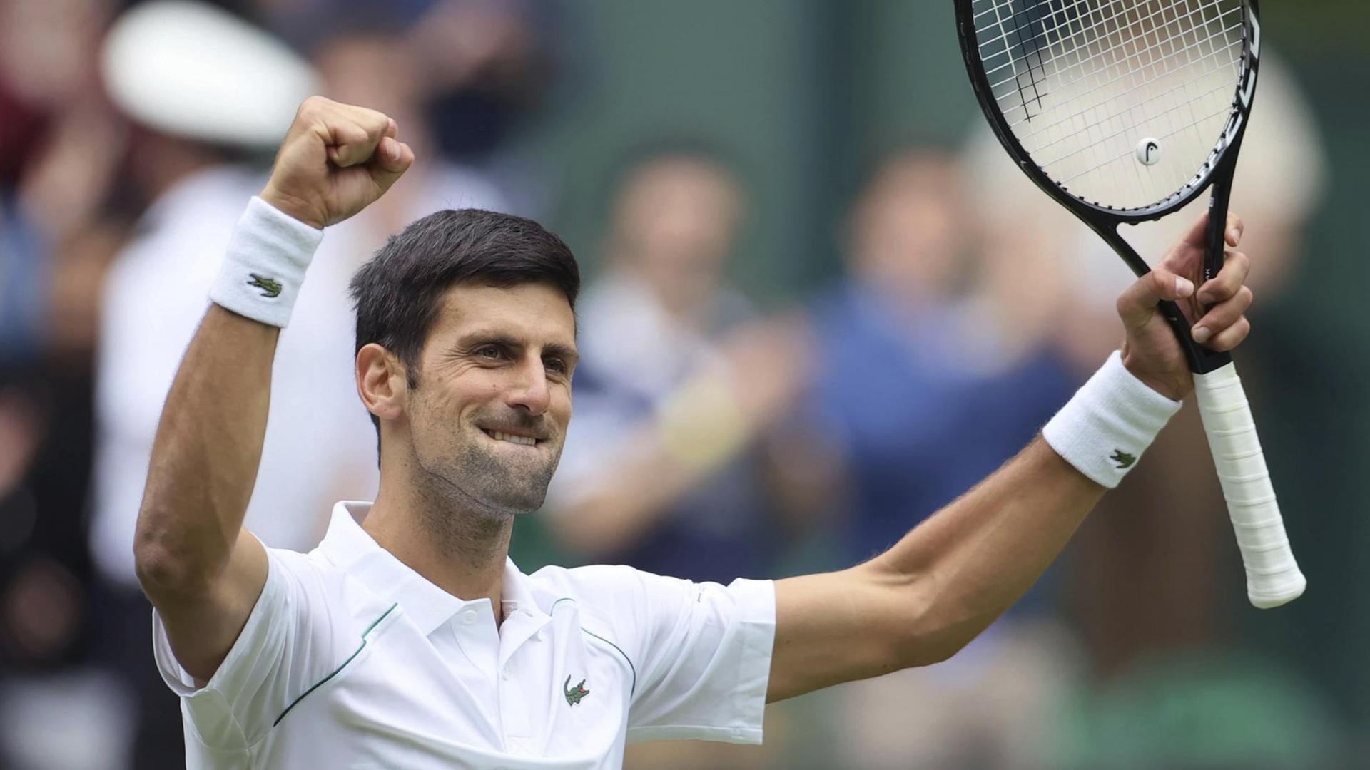Novak Djokovic hält seinen Tennis-Schläger hoch und hebt die andere Hand zur Faust geballt nach oben. Novak Djokovic hält seinen Tennis-Schläger hoch und hebt die andere Hand zur Faust geballt nach oben.