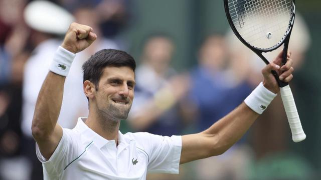 Novak Djokovic hält seinen Tennis-Schläger hoch und hebt die andere Hand zur Faust geballt nach oben.