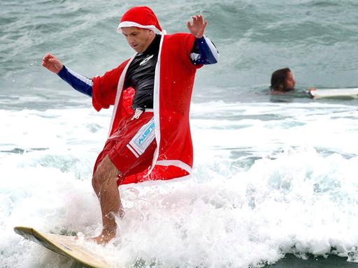 Ein Weihnachtsmann surft am Bondi Beach in Sydney, Australien.