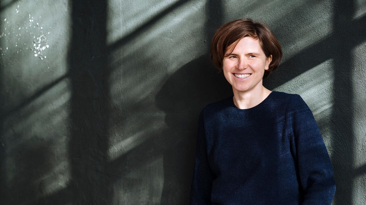 Judith Schalansky steht vor einer Wand, sie schaut freundlich rechts an der Kamera vorbei Judith Schalansky steht vor einer Wand, sie schaut freundlich rechts an der Kamera vorbei