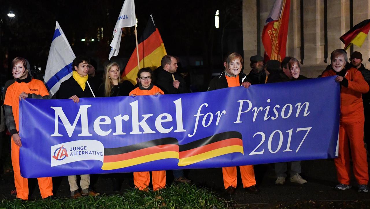 Demonstranten der "Jungen Alternative" in Jena wollen Angela Merkel 2017 im Gefängnis sehen – eine Kopie der "Lock Her Up"-Kampagne von Donald Trump gegen Hillary Clinton in den USA.