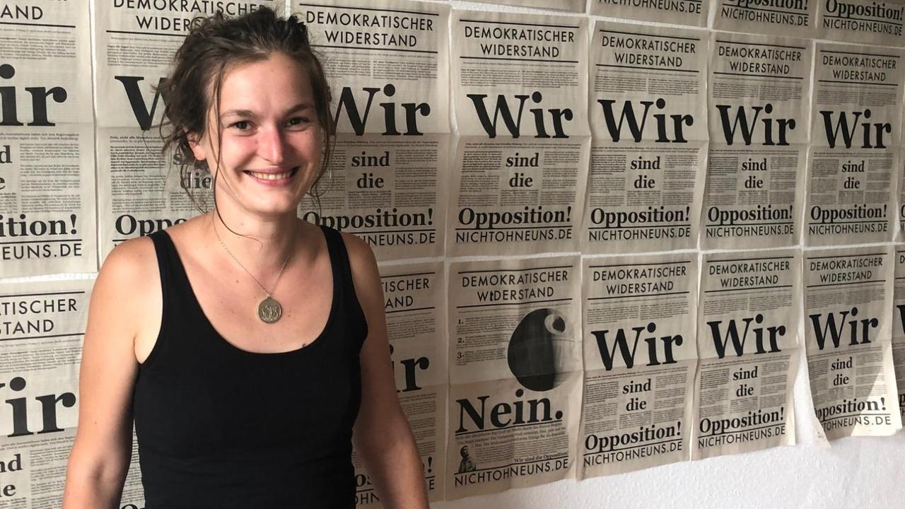 Eine junge Frau steht vor einer Wand mit den Titelseiten der Protestzeitung "Demokratischer Widerstand". Eine junge Frau steht vor einer Wand mit den Titelseiten der Protestzeitung "Demokratischer Widerstand".