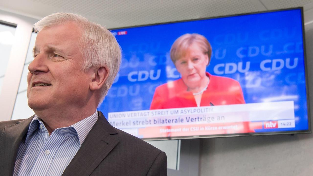 Horst Seehofer, CSU-Vorsitzender und Bundesminister für Inneres, Heimat und Bau, läuft auf seinem Weg zu einer Pressekonferenz, die in Anschluss an die Sitzung des CSU-Vorstands stattfindet, an einem Fernseher vorbei, auf dem die Pressekonferenz von Bundeskanzlerin Angela Merkel (CDU) übertragen wird. Horst Seehofer, CSU-Vorsitzender und Bundesminister für Inneres, Heimat und Bau, läuft auf seinem Weg zu einer Pressekonferenz, die in Anschluss an die Sitzung des CSU-Vorstands stattfindet, an einem Fernseher vorbei, auf dem die Pressekonferenz von Bundeskanzlerin Angela Merkel (CDU) übertragen wird.