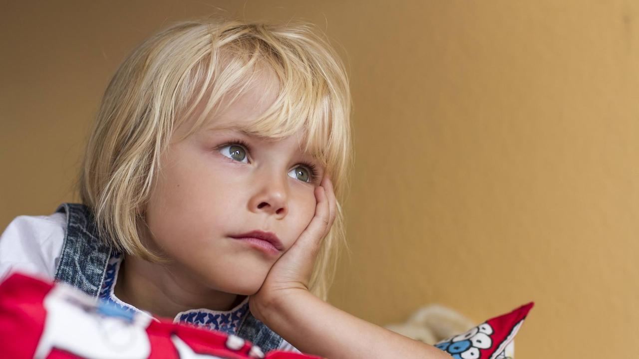 Ein blondes Mädchen hat den Kopf auf die Hand gestützt. Ein blondes Mädchen hat den Kopf auf die Hand gestützt.