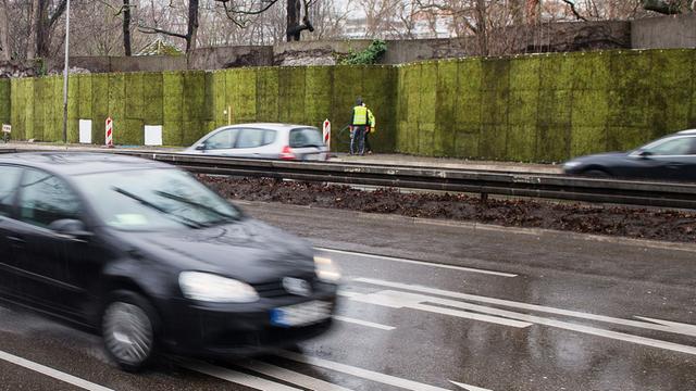 Autos fahren am 09.03.2017 in Stuttgart an der halb-fertiggestellten Mooswand aus grauem Zackenmützenmoos entlang. Sie soll in einem Pilotprojekt gegen die Feinstaubbelastung die Schadstoffe binden.