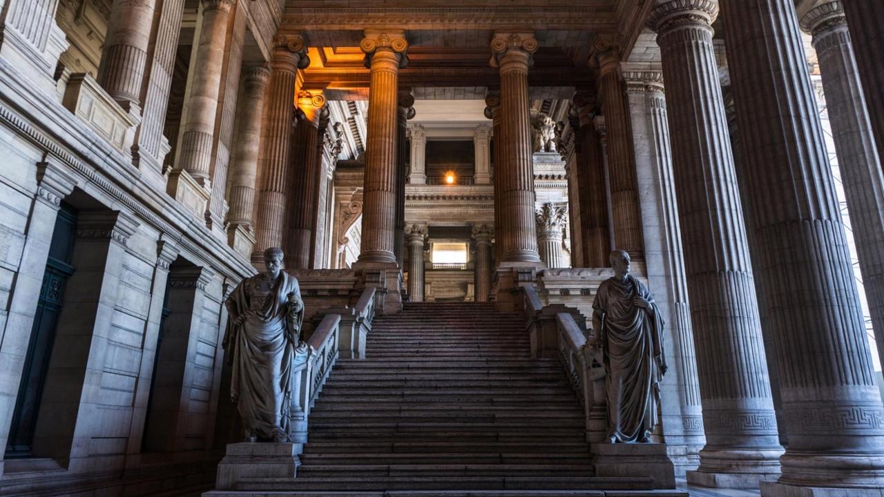 Eine breite, von Statuen und hohen Säulen gesäumte Treppe.