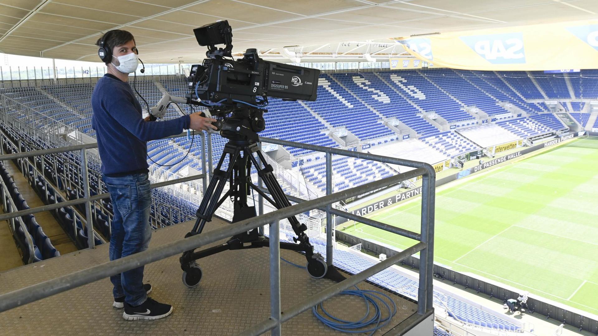 Ein Kameramann trägt im Stadion hinter seiner Fernsehkamera eine Mund-Nasen-Maske. Ein Kameramann trägt im Stadion hinter seiner Fernsehkamera eine Mund-Nasen-Maske.