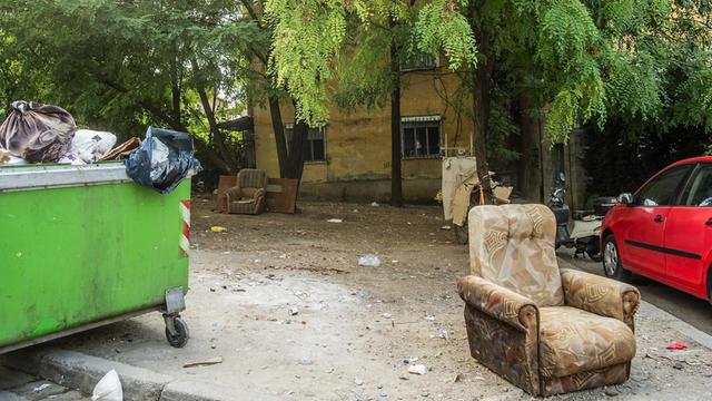 Polstermöbel stehen neben einem Müllcontainer vor einem Wohnhaus in Tirana, Albanien