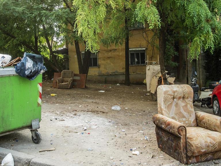 Polstermöbel stehen neben einem Müllcontainer vor einem Wohnhaus in Tirana, Albanien