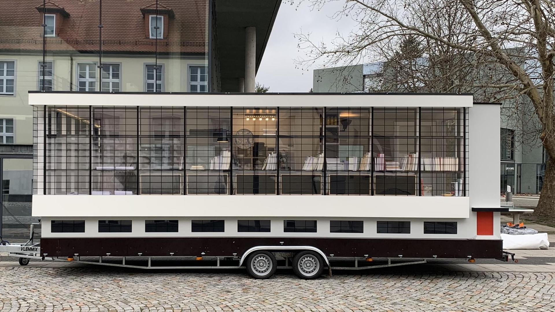 Abbildung eines dem Bauhausgebäude nachempfundenen Tiny Houses auf einem Anhänger. Abbildung eines dem Bauhausgebäude nachempfundenen Tiny Houses auf einem Anhänger.