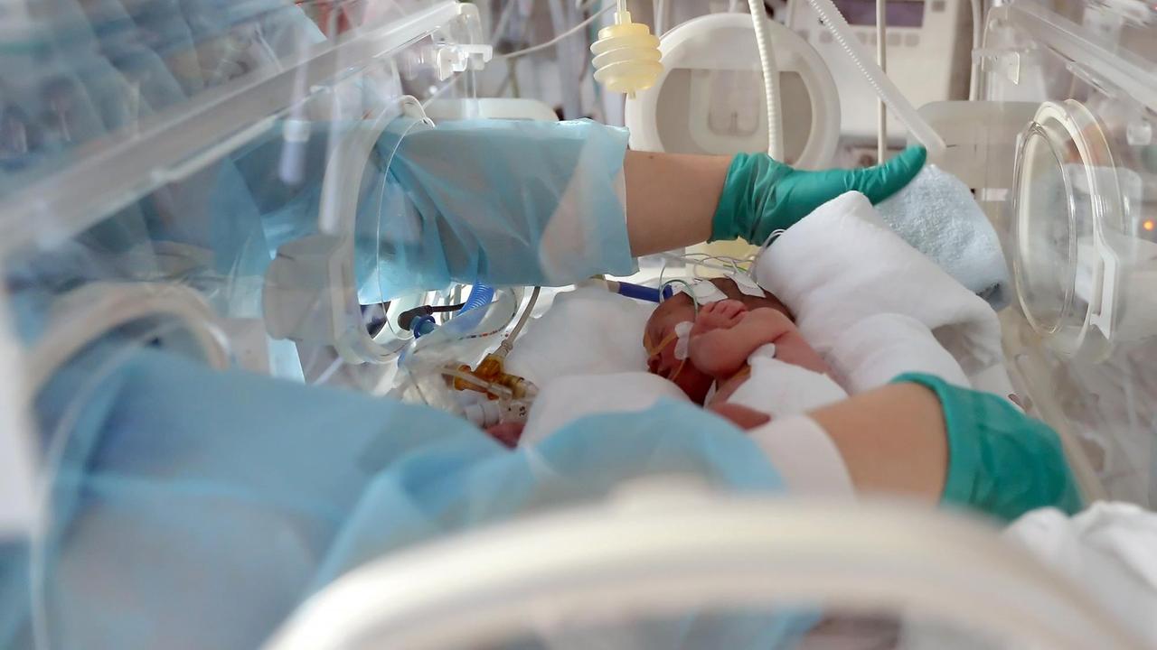 Eine Schwester versorgt am auf einer Neonatologie-Station ein zu früh geborenes Baby in einem Inkubator