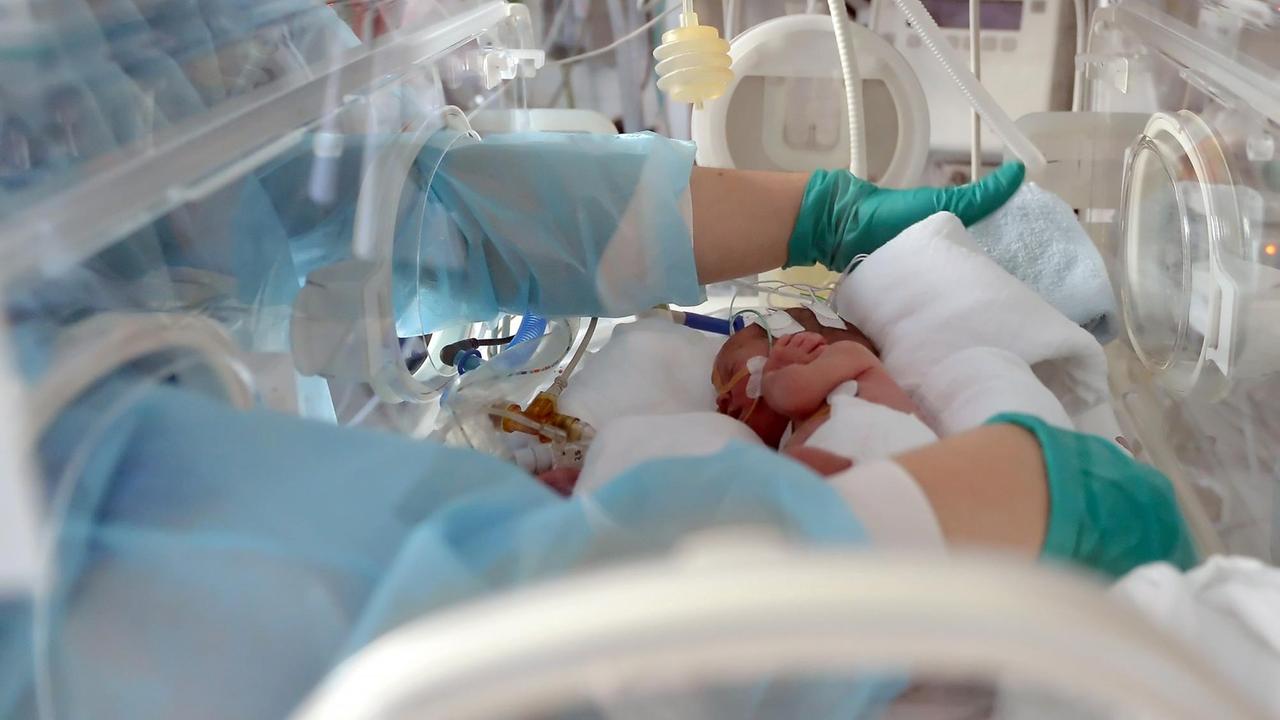 Eine Schwester versorgt am auf einer Neonatologie-Station ein zu früh geborenes Baby in einem Inkubator Eine Schwester versorgt am auf einer Neonatologie-Station ein zu früh geborenes Baby in einem Inkubator