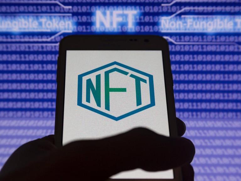 Der abkürzende Schriftzug NFT und seine Entsprechung non-fungible-token auf einem Computer-Bildschirm dargestellt.