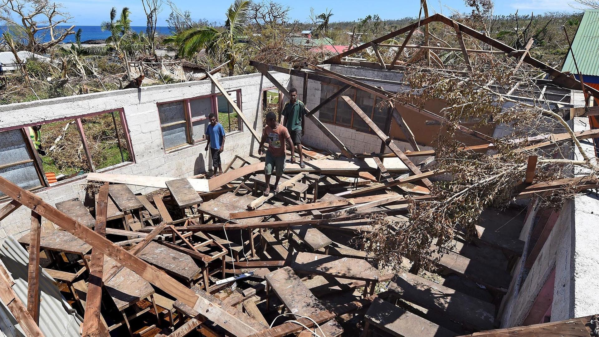 Menschen stehen in einem zerstörten Haus in Vanuatu. Menschen stehen in einem zerstörten Haus in Vanuatu.