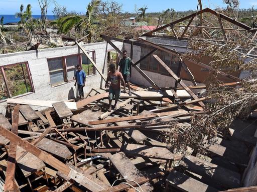 Menschen stehen in einem zerstörten Haus in Vanuatu.