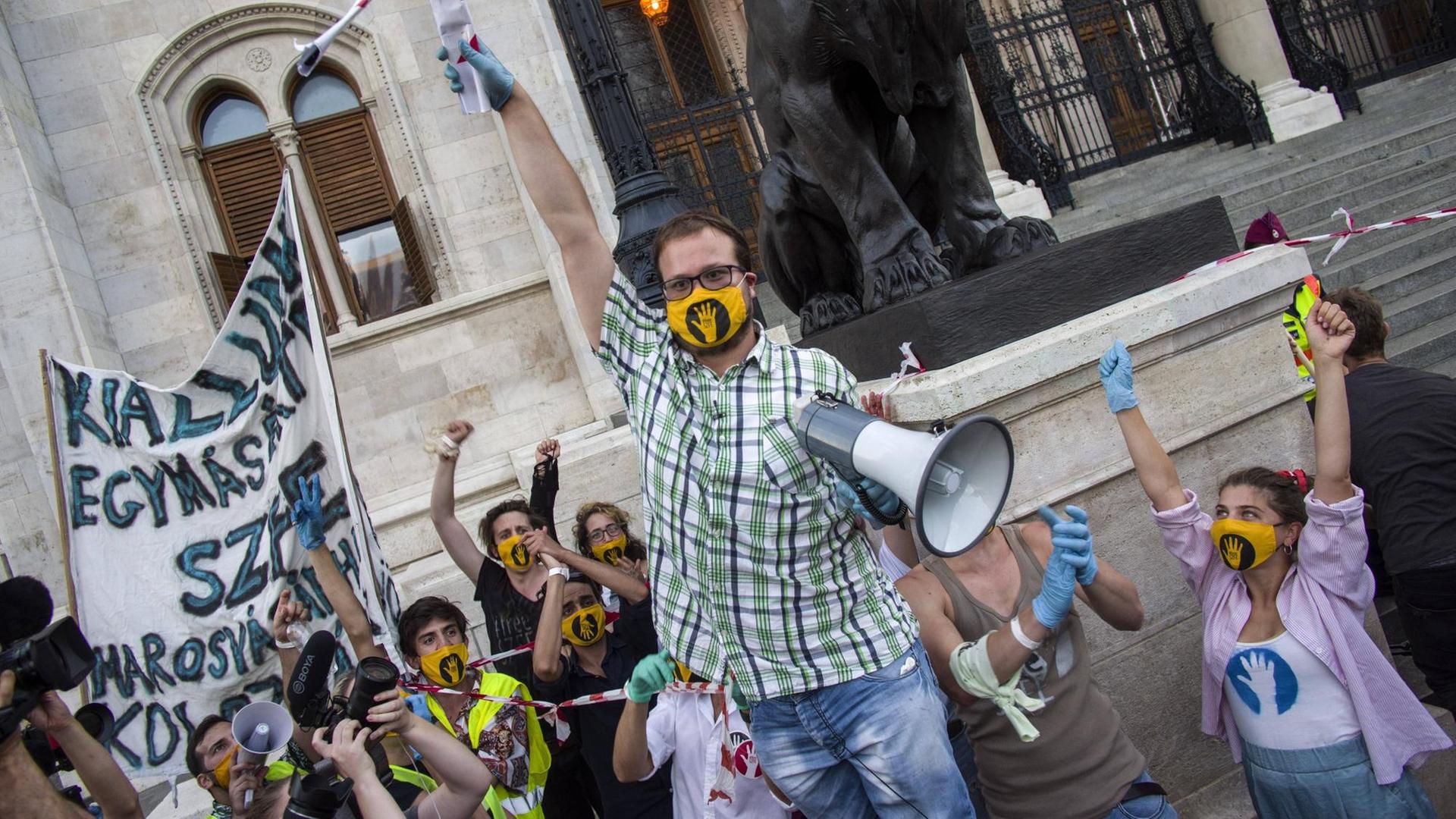 Proteste von Studenten: Einer hält ein Mikrofon. Alle tragen gelbe Masken. Proteste von Studenten: Einer hält ein Mikrofon. Alle tragen gelbe Masken.