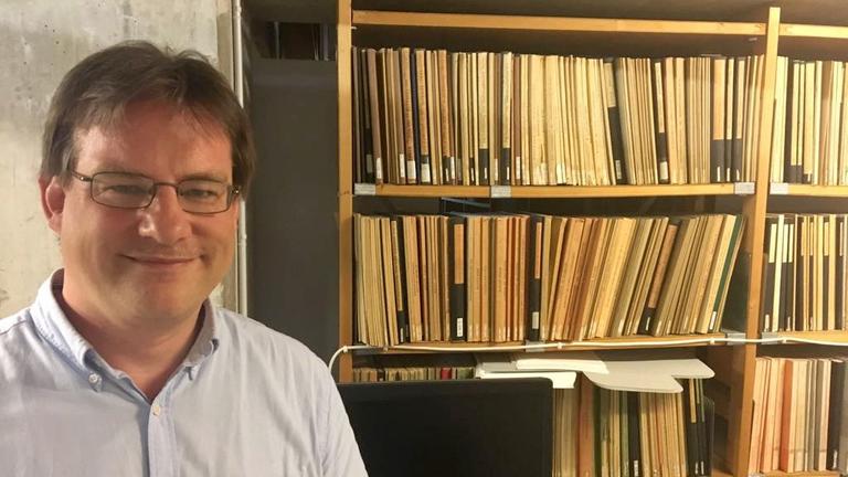Der Schweizer Historiker Christian Koller steht vor einem Bücherregal in seinem Büro