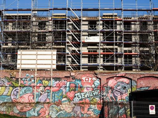 Eine Mauer mit bunten Graffiti vor einer Baustelle.