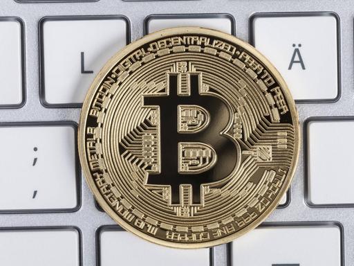 Ein Münze mit der Aufschrift Bitcoin liegt auf einer Tastatur. In Erscheinung getreten ist die Blockchain-Technik erstmals mit der rein digitalen Währung Bitcoin, jetzt soll sie auch für andere Zwecke eingesetzt werden.