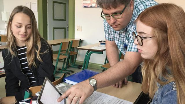 Mathelehrer Horst Kretschmer zeigt zwei Schülerinnen etwas auf dem Tablet.
