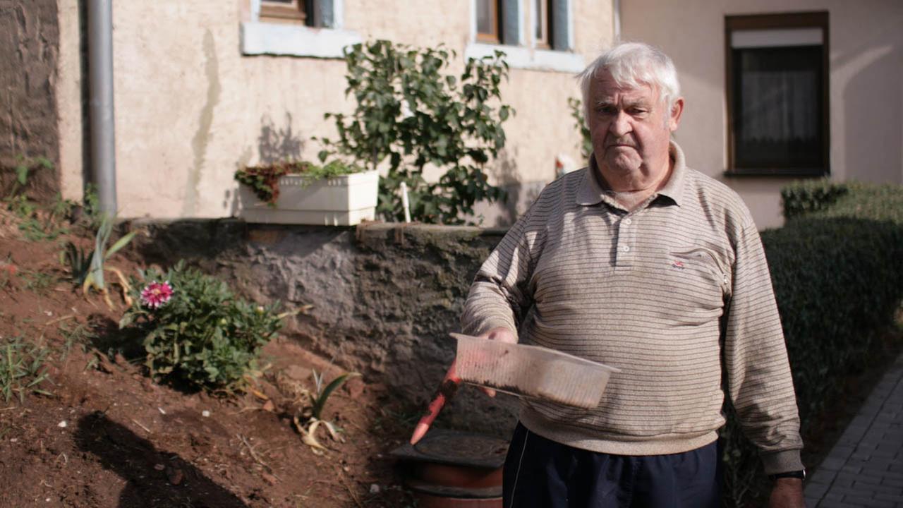Harald Lessner, Pensionär aus Göllingen, steht vor einem Haus und schaut in die Kamera