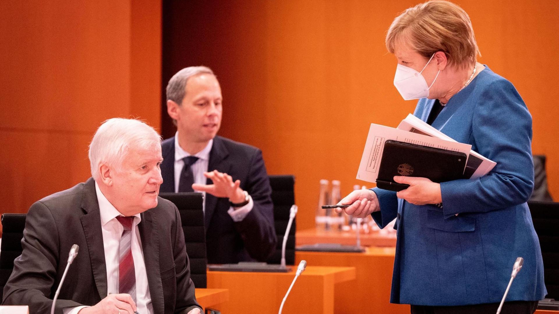 Bundeskanzlerin Angela Merkel (CDU) und Horst Seehofer (CSU - l), Bundesminister des Innern, für Bau und Heimat, unterhalten sich vor Hendrik Hoppenstedt (M), Staatsminister bei der Bundeskanzlerin, zu Beginn der Sitzung des Bundeskabinetts im Bundeskanzleramt.