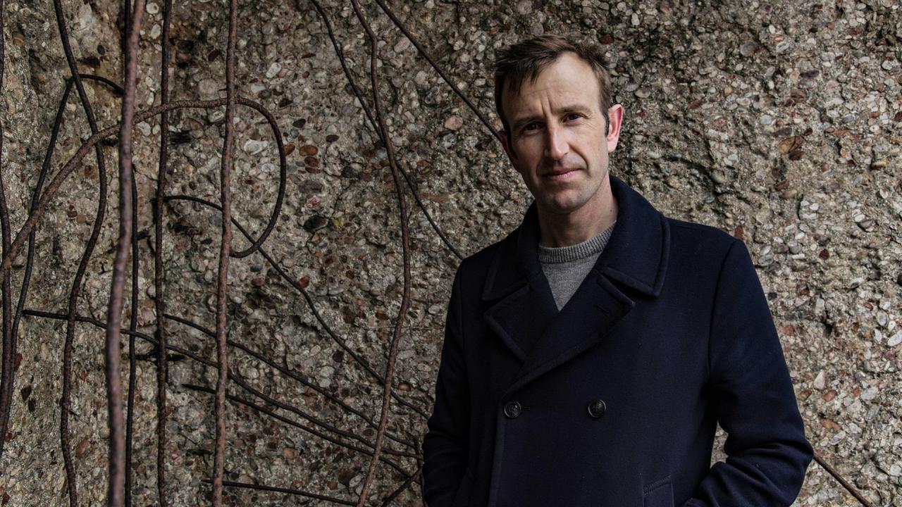 Der Schriftsteller Robert Macfarlane steht vor einer Wand, von der Wurzeln herabhängen. Der Schriftsteller Robert Macfarlane steht vor einer Wand, von der Wurzeln herabhängen.