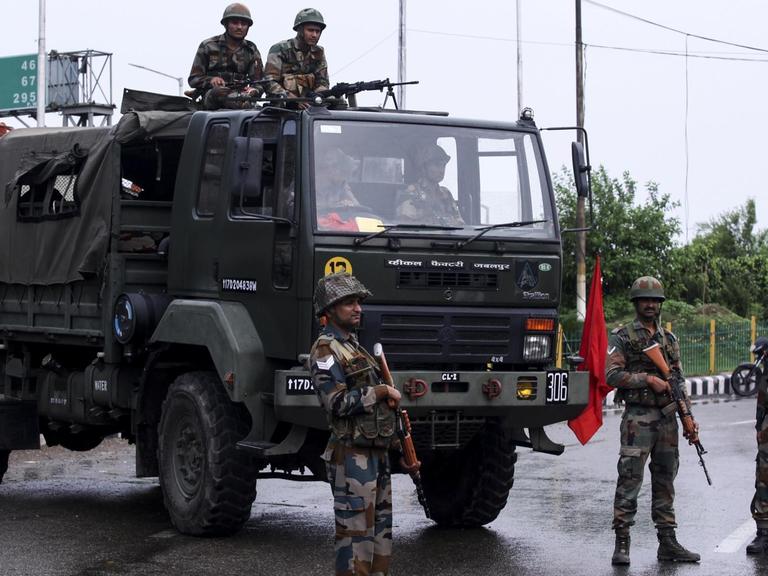 Bewaffnete Soldaten stehen bei einem Armee-Laster auf einer Straße