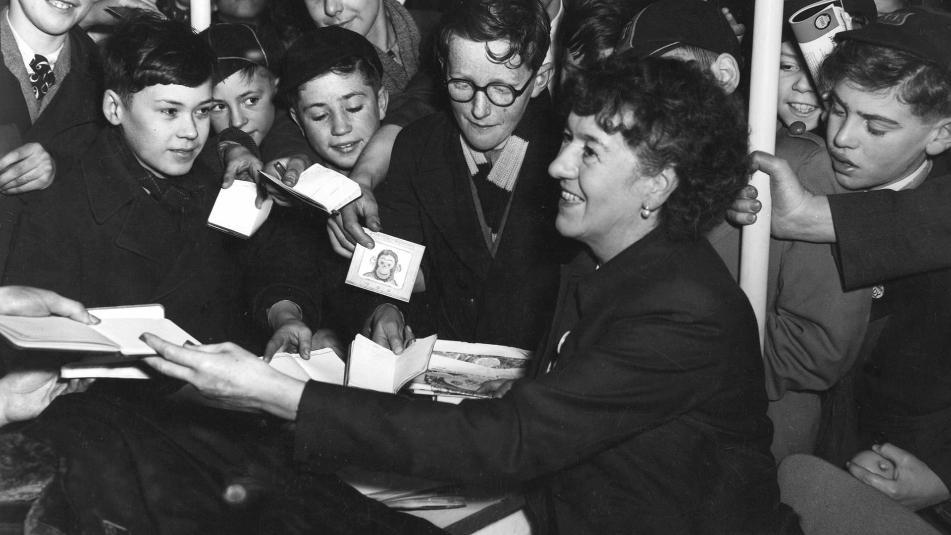 Die Schriftstellerin Enid Blyton umringt von Schuljungen während einer Autogrammstunde im Jahr 1953.