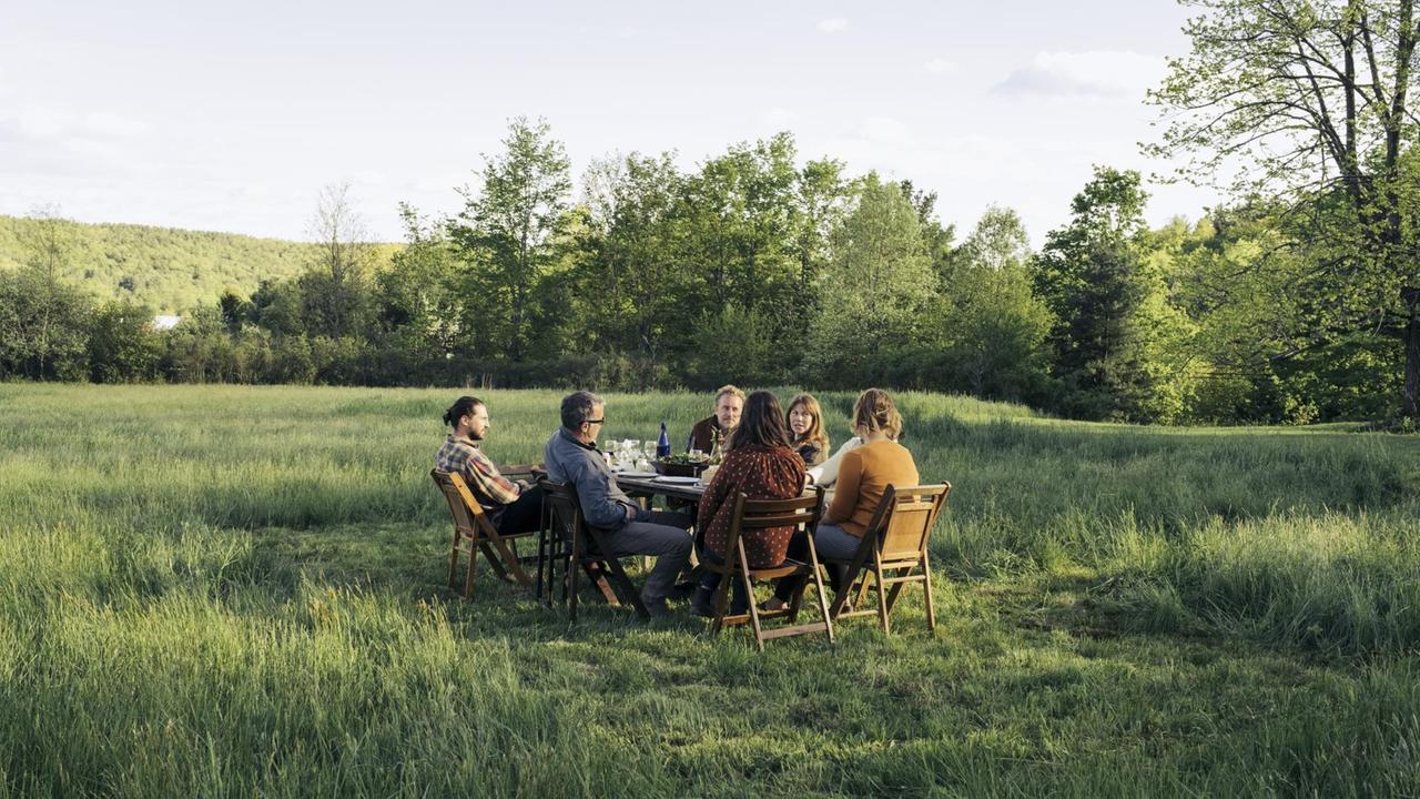 Zusammen genießen eine Gruppe von Freunden ein gemeinsames Essen auf einer grünen Wiese. Zusammen genießen eine Gruppe von Freunden ein gemeinsames Essen auf einer grünen Wiese.
