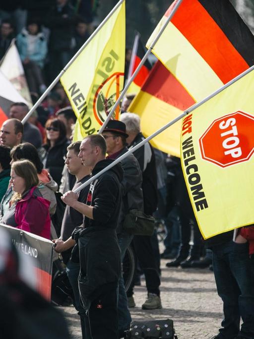 Pegida-Anhänger in Dresden mit Fahnen, auf denen ein Stopp für Flüchtlinge gefordert wird