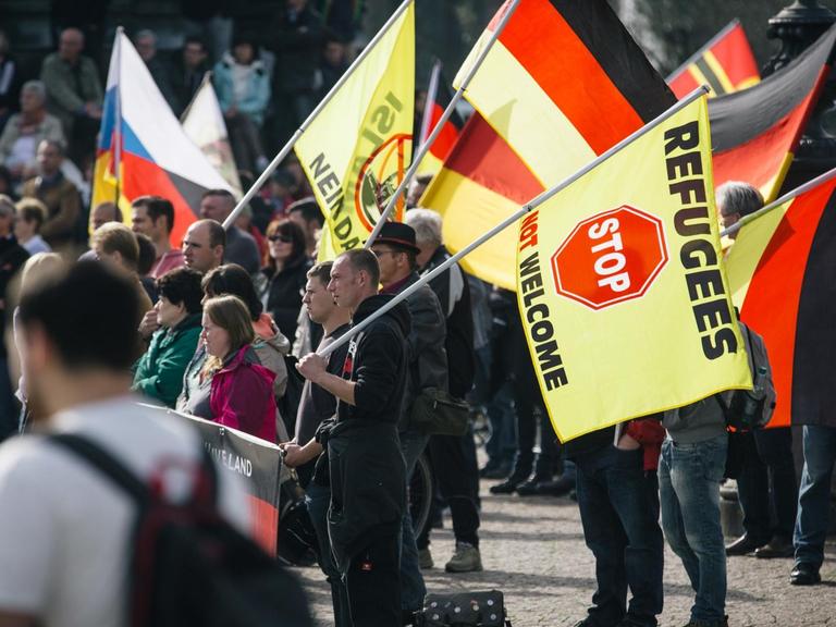 Pegida-Anhänger in Dresden mit Fahnen, auf denen ein Stopp für Flüchtlinge gefordert wird