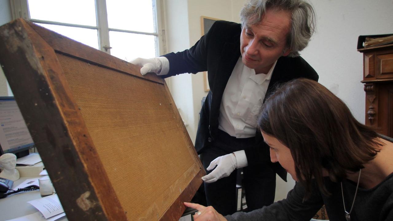 Die Experten für Provenzienzforschung im Museum Wiesbaden, Miriam Merz und Peter Forster, untersuchen am 10.12.2013 im Landesmuseum Wiesbaden (Hessen) die Rückseite eines Bildes. Das Museum Wiesbaden hat 1999 begonnen, alle zwischen 1933 und 1945 erworbenen Kunstwerke auf ihre Herkunft zu überprüfen. Die Experten für Provenzienzforschung im Museum Wiesbaden, Miriam Merz und Peter Forster, untersuchen am 10.12.2013 im Landesmuseum Wiesbaden (Hessen) die Rückseite eines Bildes. Das Museum Wiesbaden hat 1999 begonnen, alle zwischen 1933 und 1945 erworbenen Kunstwerke auf ihre Herkunft zu überprüfen.