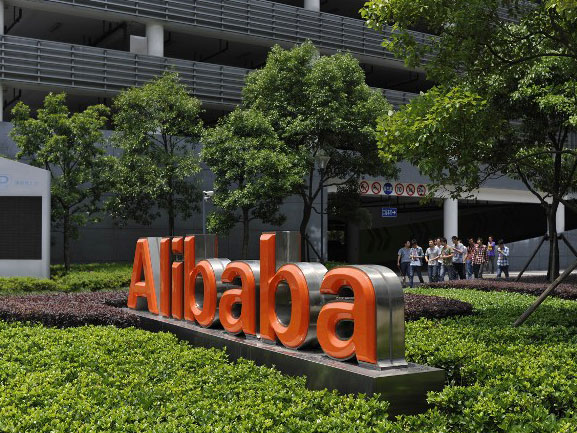 Chinesische Arbeiter verlassen das Alibaba-Hauptquartier im Osten Chinas, vor dem der Alibaba-Schriftzug zu sehen ist.