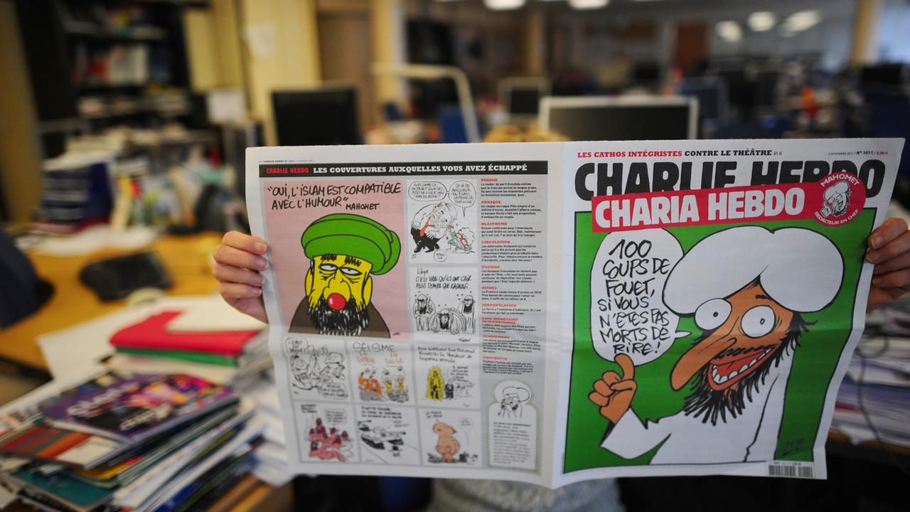 Jemand liest eine ältere Ausgabe von "Charlie Hebdo" mit einer Mohammed-Karikatur auf dem Titel. Jemand liest eine ältere Ausgabe von "Charlie Hebdo" mit einer Mohammed-Karikatur auf dem Titel.
