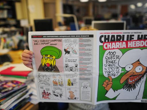 Jemand liest eine ältere Ausgabe von "Charlie Hebdo" mit einer Mohammed-Karikatur auf dem Titel.