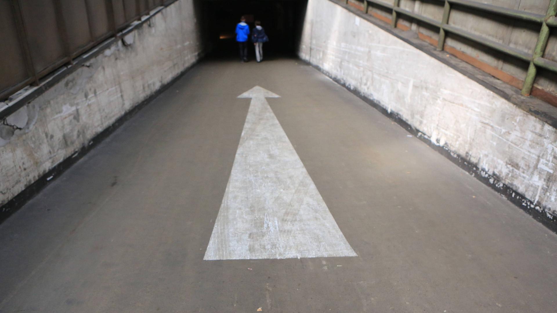 Blick in einen Tunnel in den zwei Fußgänger laufen.