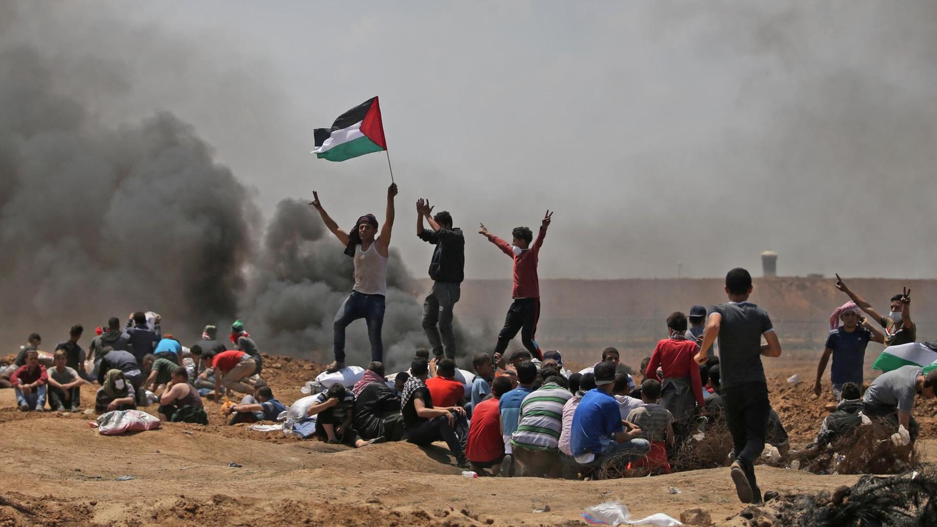 Das Bild zeigt Palästinenser bei Dschabaliya im Gazastreifen, die ihre Nationalflagge schwenken und nahe der Grenze zu Israel demonstrieren.