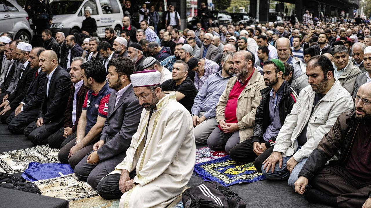 Viele Muslime knien auf dem Boden und sprechen ein Friedensgebet gegen Extremismus in Kreuzberg, Berlin in Deutschland.