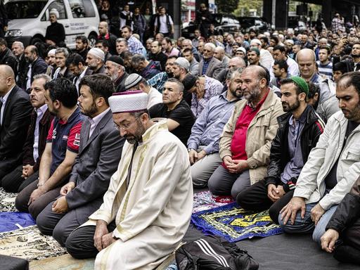 Muslime knien auf dem Boden und sprechen ein Friedensgebet gegen Extremismus in Berlin. 