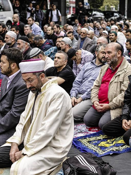 Viele Muslime knien auf dem Boden und sprechen ein Friedensgebet gegen Extremismus in Kreuzberg, Berlin in Deutschland. Islamische Verbände halten Friedensgebet vor der Mevlana-Moschee ab, vor der vor einem Monat ein Brandanschlag verübt wurde. Eine Aktion des Zentralrats der Muslime, der Türkisch-Islamischen Union (Ditib), des Islamrates und dem Verband der Islamischen Kulturzentren (VIKZ).