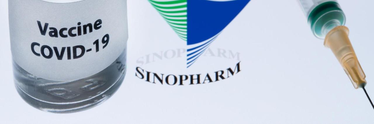 Ein Fläschen mit Corona-Impfstoff, daneben das Logo des chinesischen Unternehmens Sinopharm.