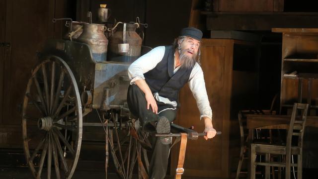Sänger Max Hopp sitzt als Milchmann Tevje im Musical "Anatevka" in der Komischen Oper in Berlin auf einem Milchwagen.