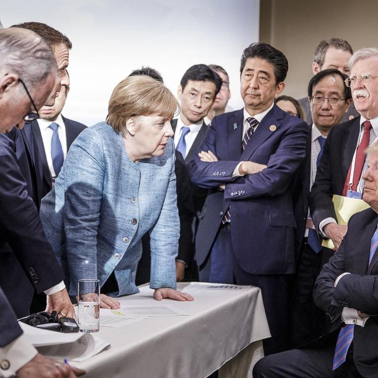 Merkel spricht mit Trump während Macron, Abe und Bolton zuhören. Merkel spricht mit Trump während Macron, Abe und Bolton zuhören.