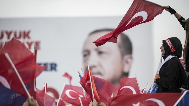 Anhänger des türkischen Präsidenten Recep Tayyip Erdogan verfolgen fahnenschwingend eine seiner Wahlkampfreden. 