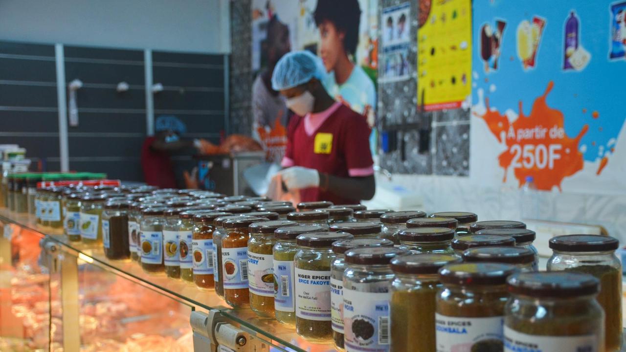Lokale Gewürze stehen aneinandergereiht, in Glasflachen verpackt, auf der Theke eines Supermarktes in Bamako, Mali. Lokale Gewürze stehen aneinandergereiht, in Glasflachen verpackt, auf der Theke eines Supermarktes in Bamako, Mali.