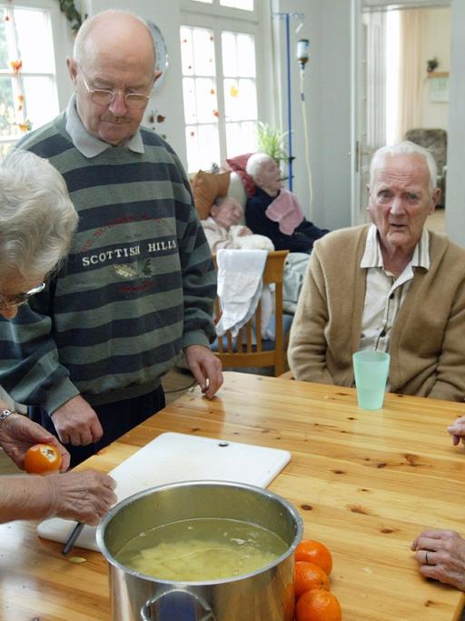 Senioren einer Wohngemeinschaft bei der Zubereitung des Mittagessens