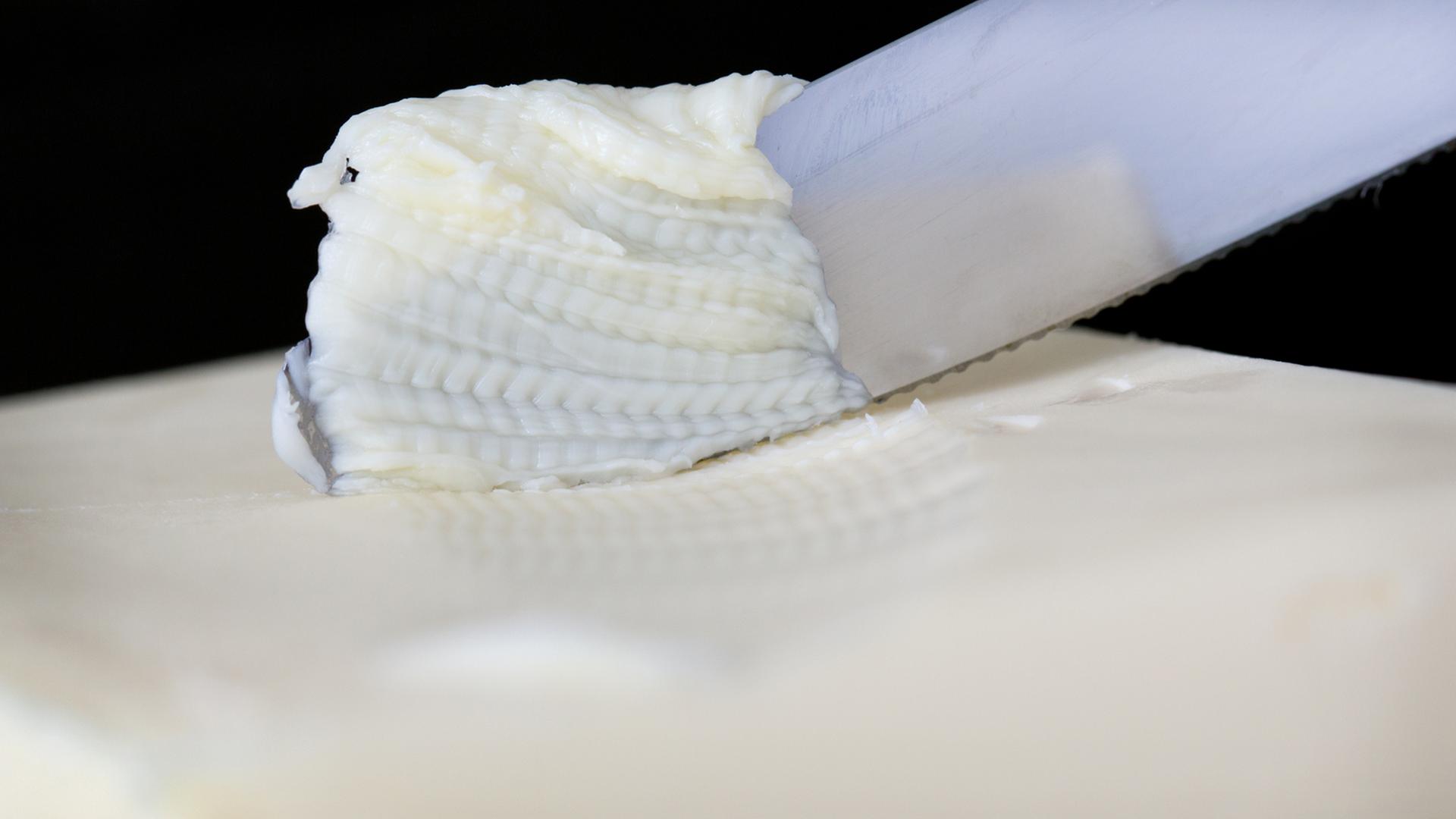 Ein Messer streicht über ein Stück Butter. Ein Messer streicht über ein Stück Butter.